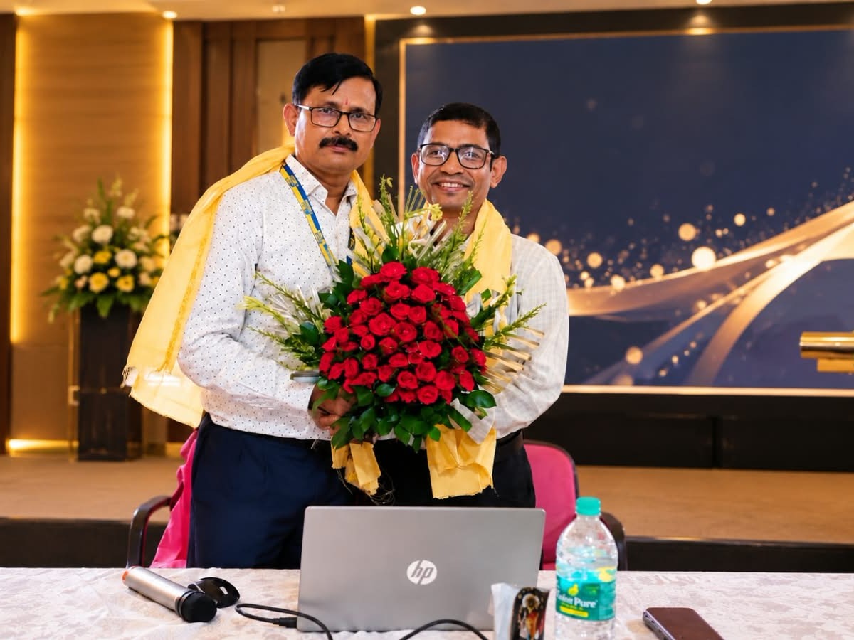 Advisor and a guest holding a flower bouquet after being felicitated on a conference stage